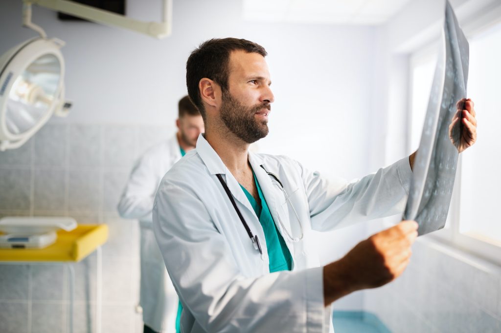 Portrait of young doctor checking X-Ray in hospital to make diagnosis